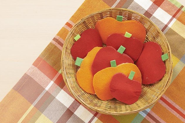 A wicker basket of pretend apples and pumpkins.