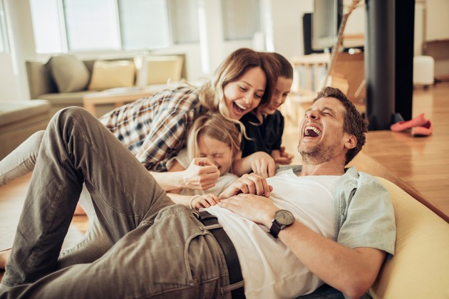 A family laughing together on the floor.