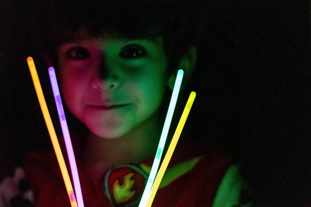 Child’s face illuminated in the dark with glow sticks. 