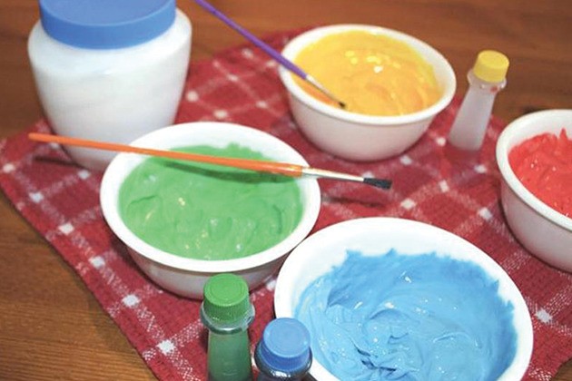 Bowls of colorful face paint and brushes on table.