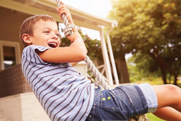 Child playing on a swinging rope outside.