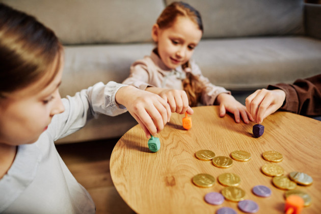 Two children playing with dreidels and gelt