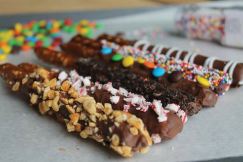 Chocolate-covered pretzel rods with various candy toppings.